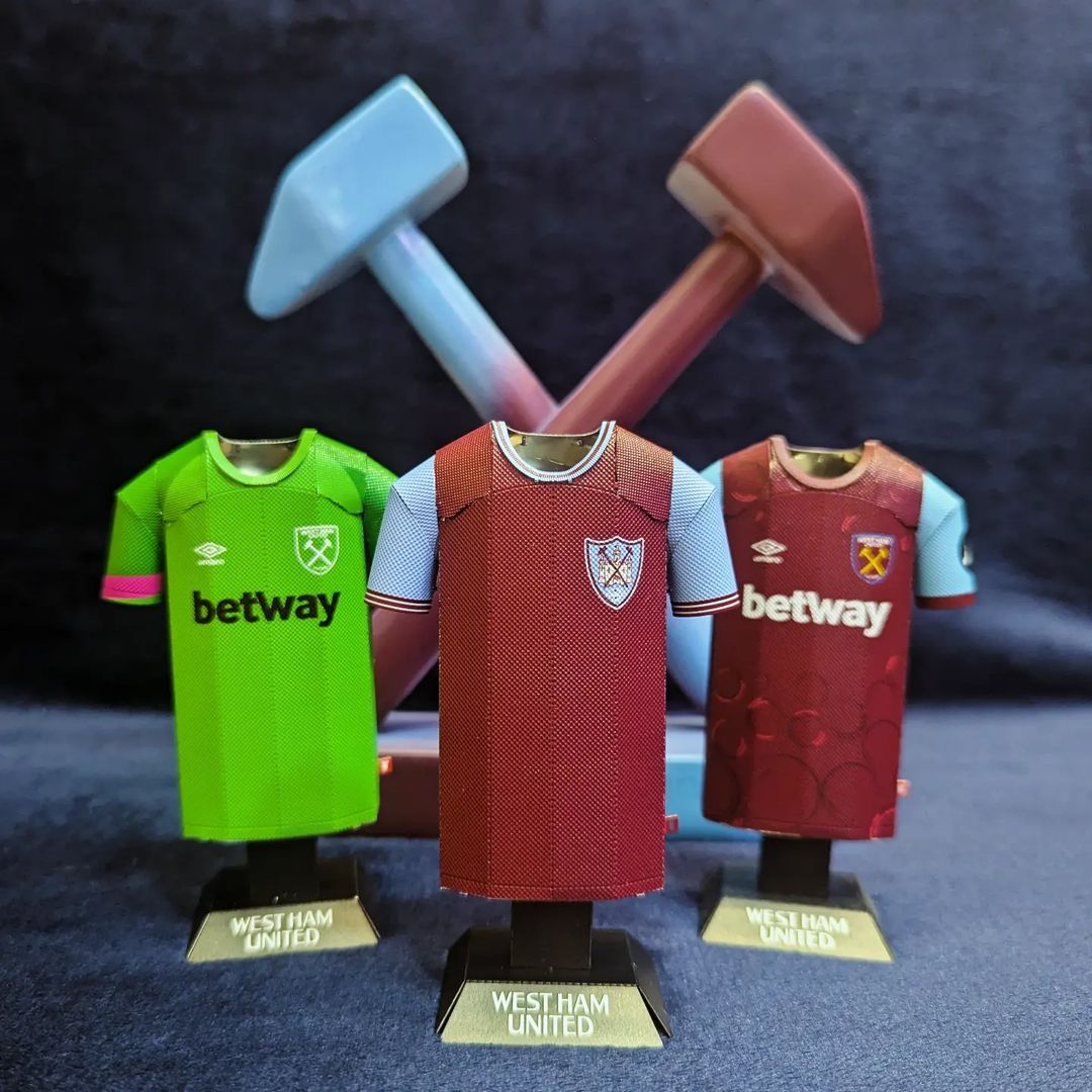 West Ham United 23/24 home and goalkeeper metal jersey collectibles with 1965 retro on display.